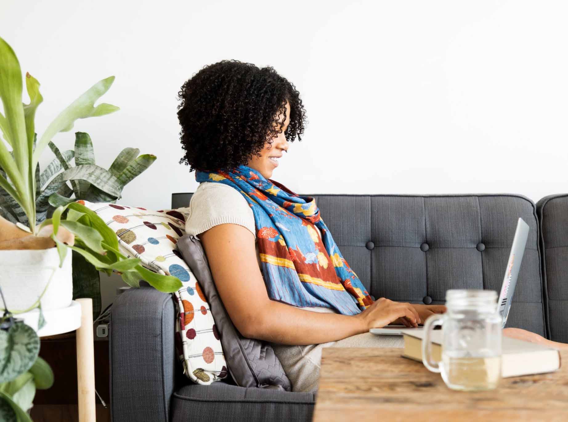 Woman on couch working on a laptop