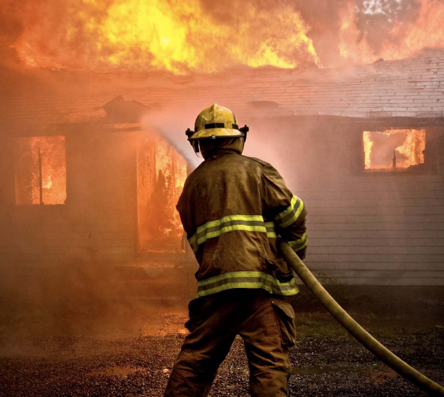 Firefighter dousing a burning home