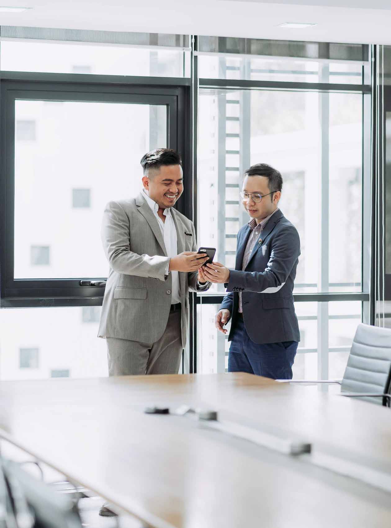 Two men looking at a phone in a conference room